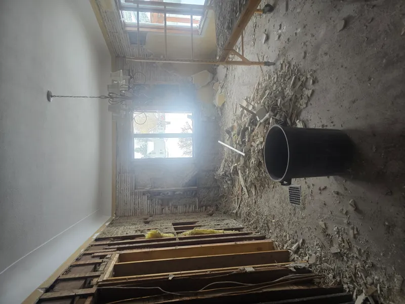 Construction debris removal — exposed framing and drywall stripped from walls