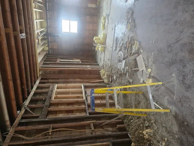 Interior demolition debris with exposed wall framing and ceiling joists