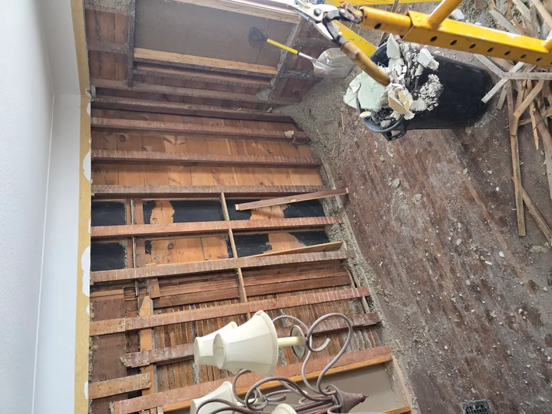 Room stripped to studs with mini excavator removing debris