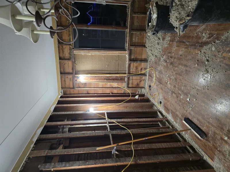 Construction debris cleanup — subfloor and framing visible
